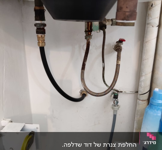 צינורות מתכת וגומי מתחת לכיור עם ברזים